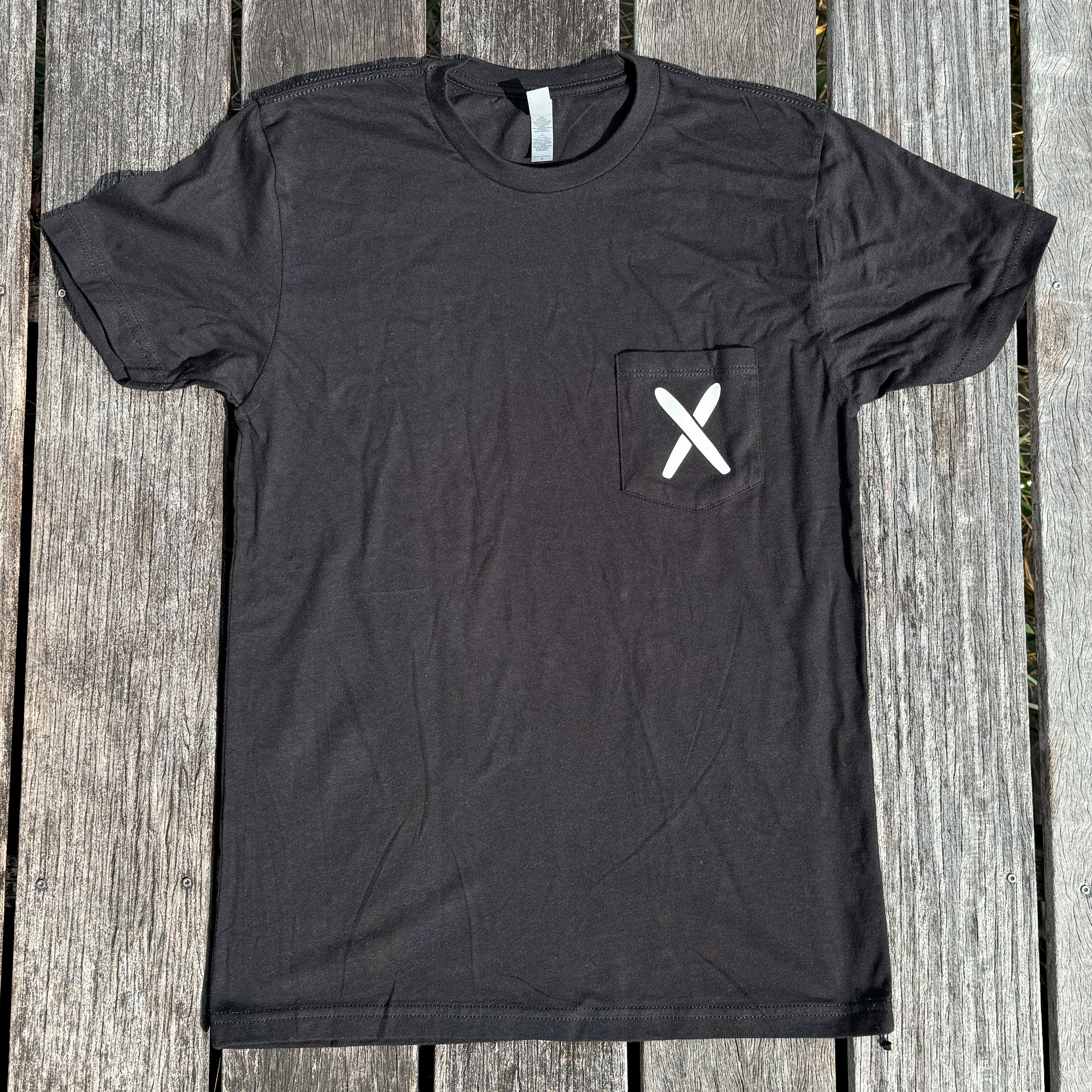 Black t-shirt with a white 'X' on a wooden surface