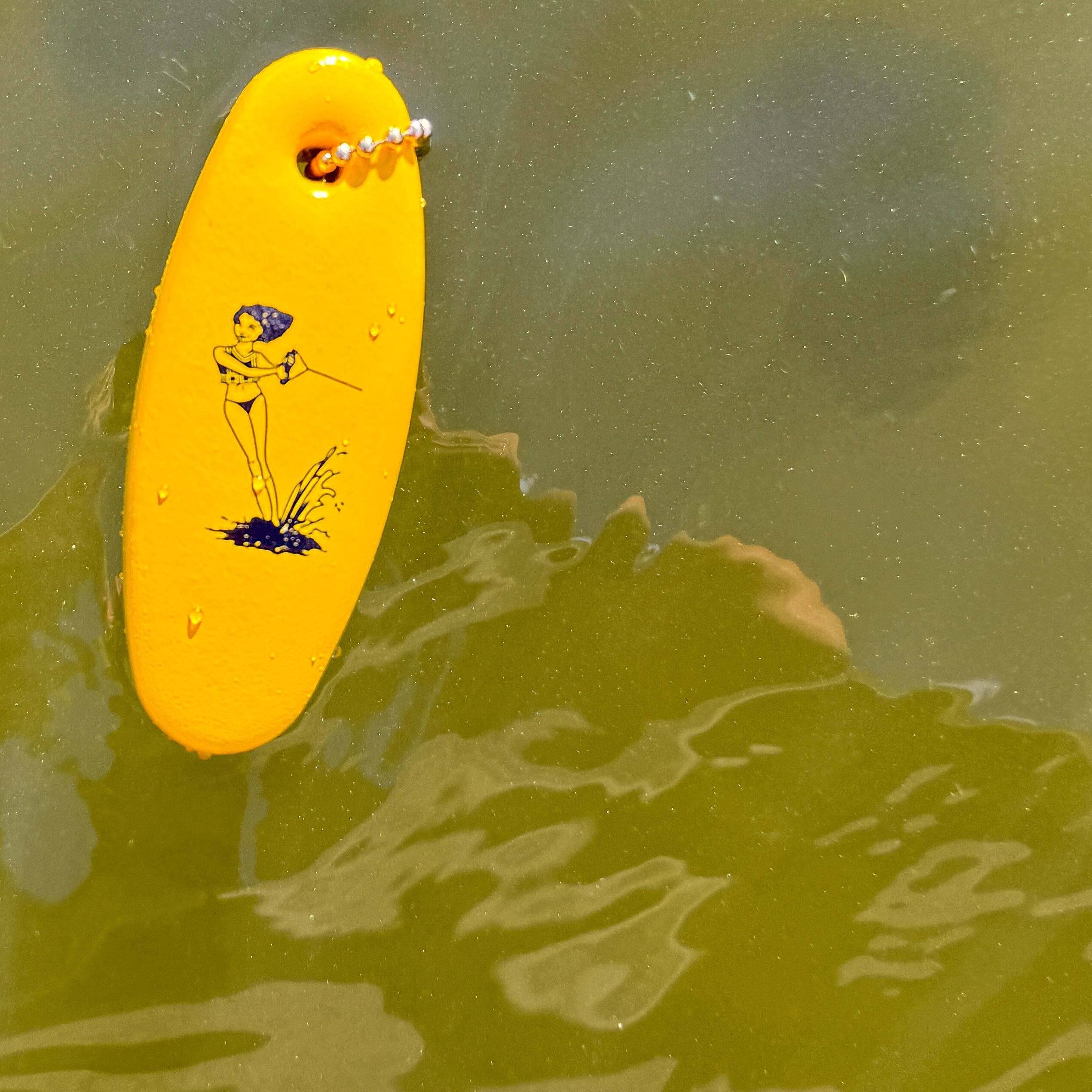 Yellow floaty keychain with a design on a greenish water background