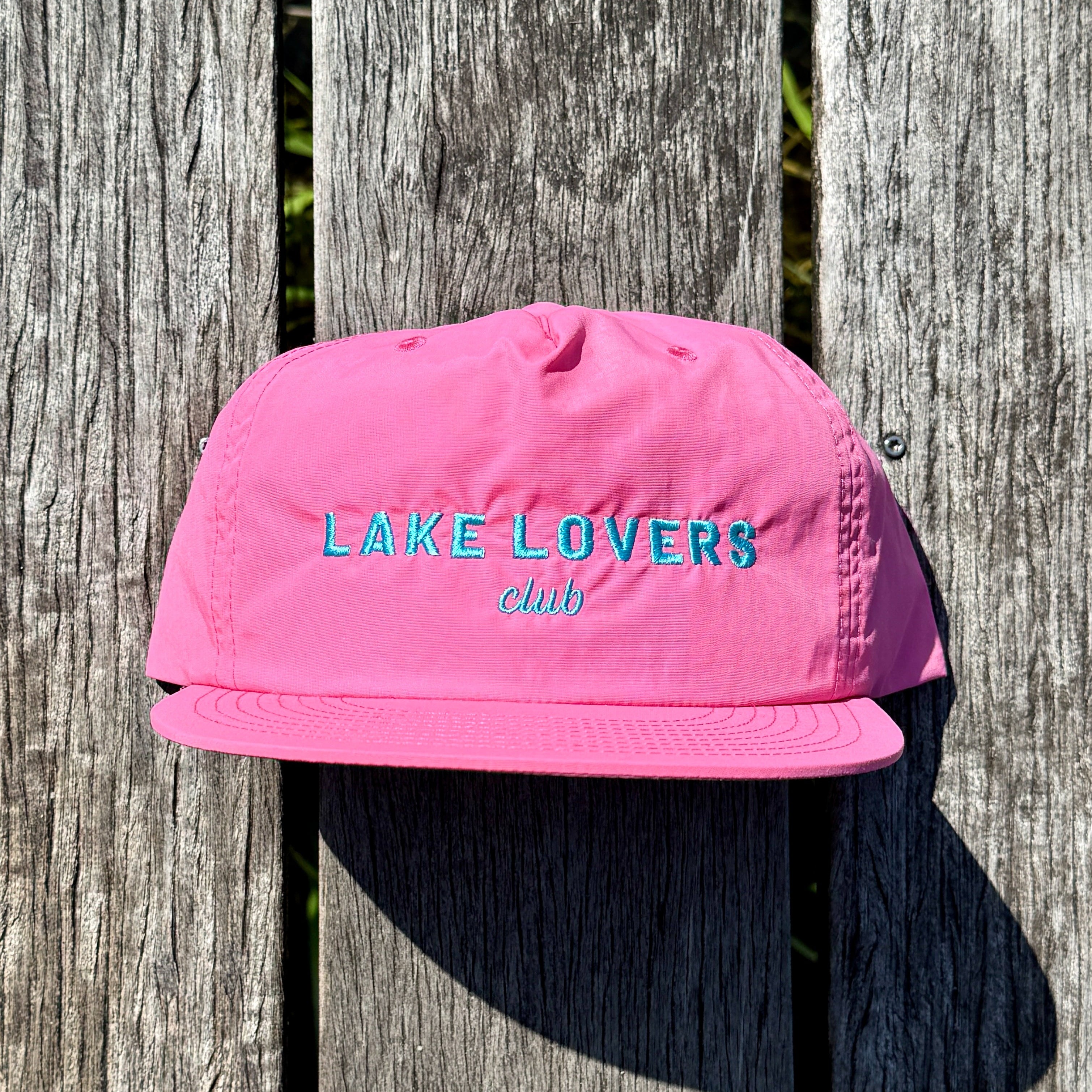 Pink cap with 'Lake Lovers Club' text on a wooden background