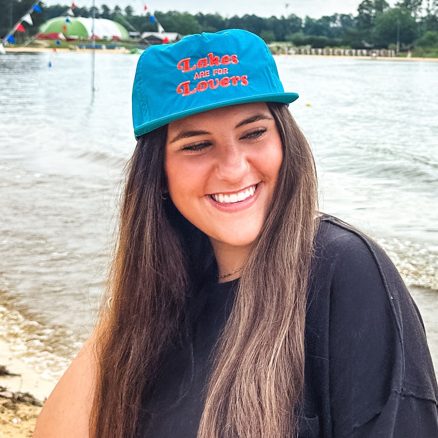 Person wearing a blue cap with text by a body of water