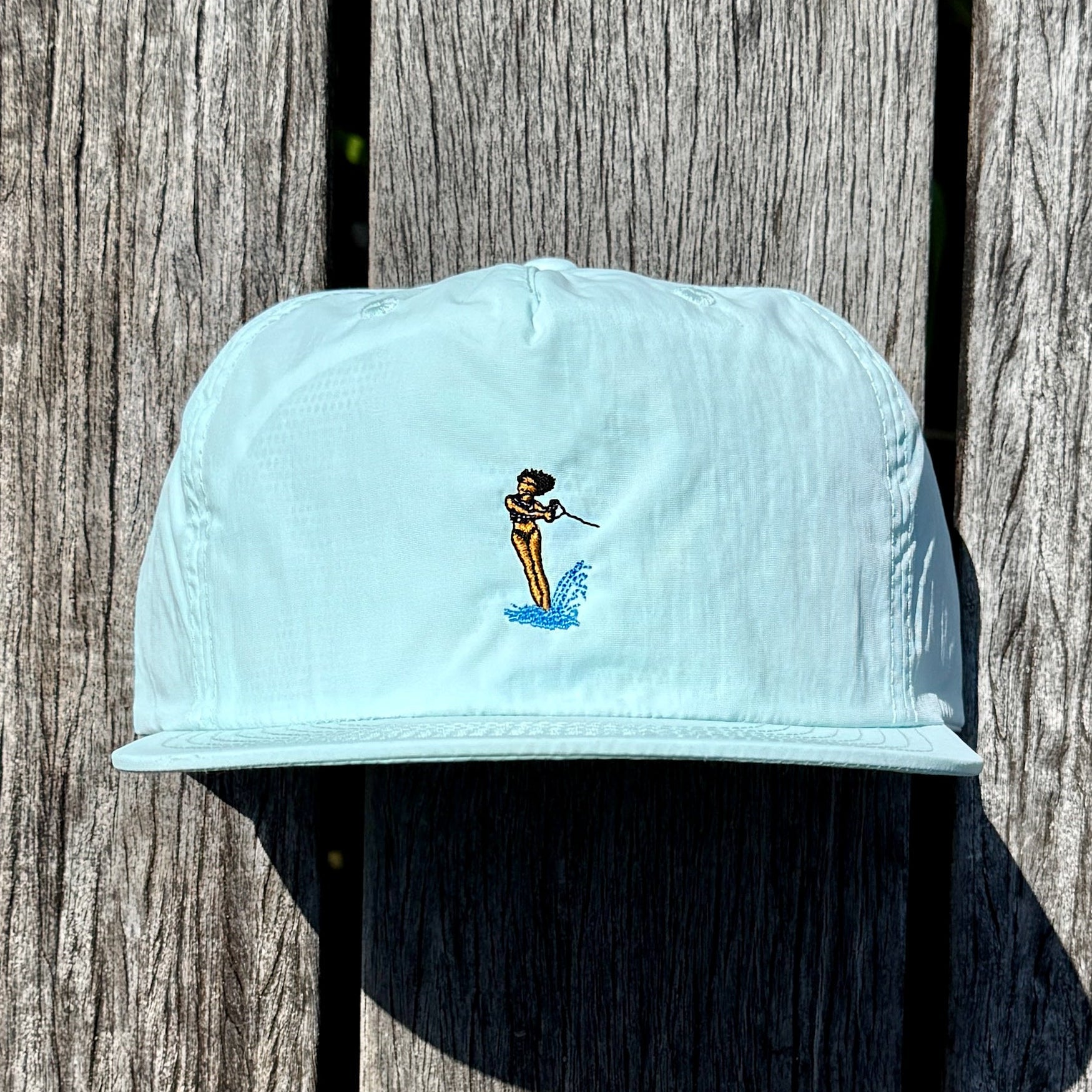 Light blue cap with a small embroidered design on a wooden surface