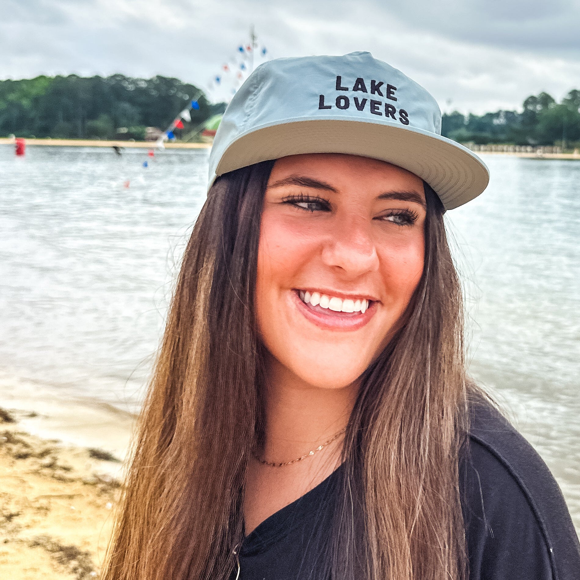 Woman wearing a 'Lake Lovers' cap by a lake