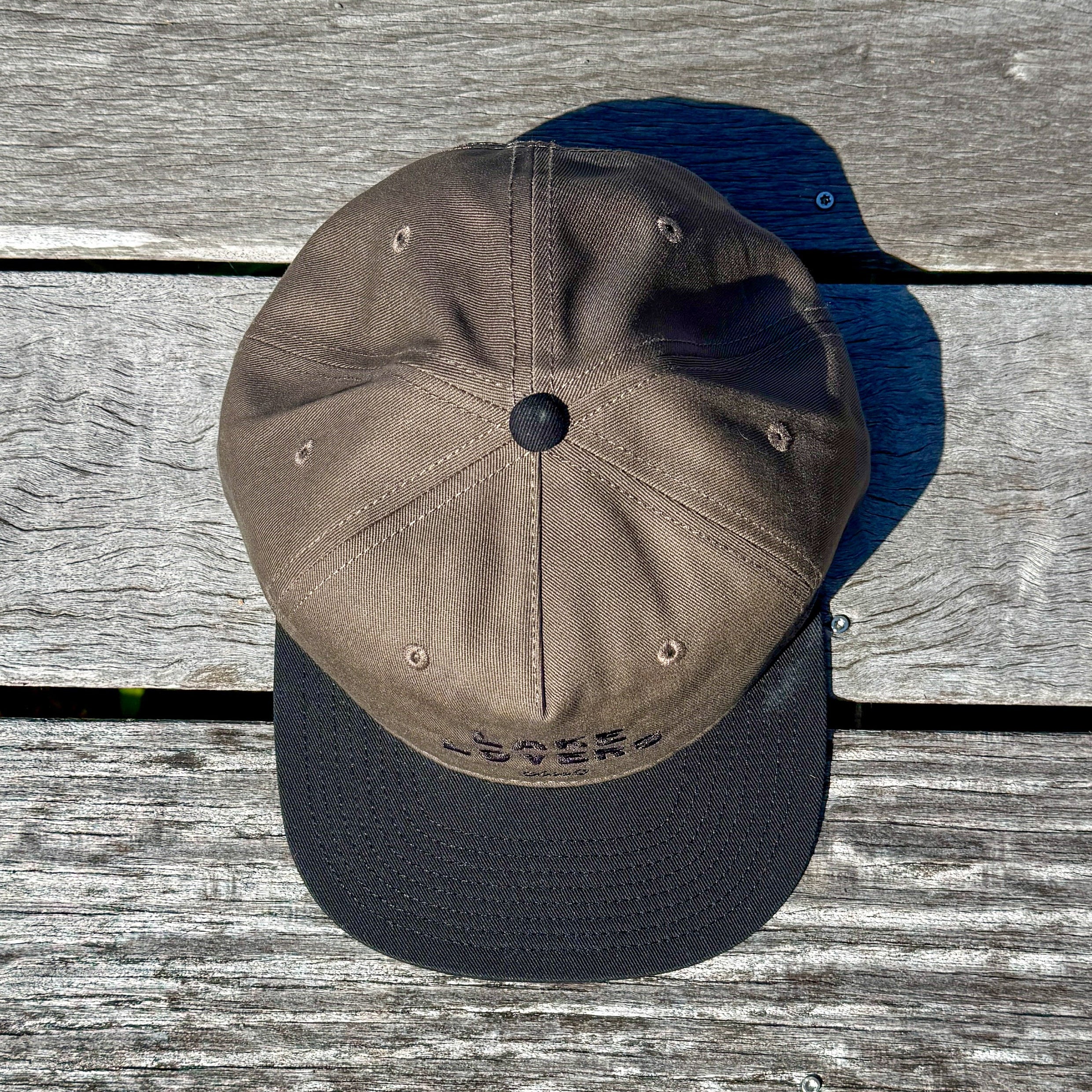 A brown and black baseball cap on a wooden surface.