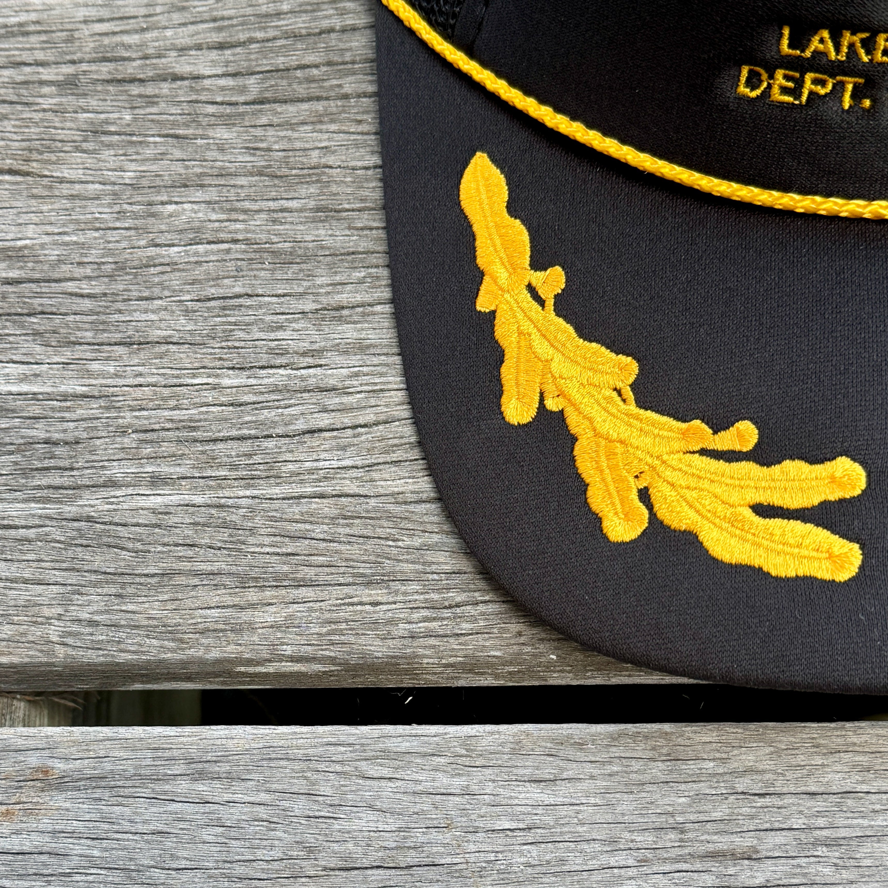 Black cap with yellow embroidered design on a wooden surface