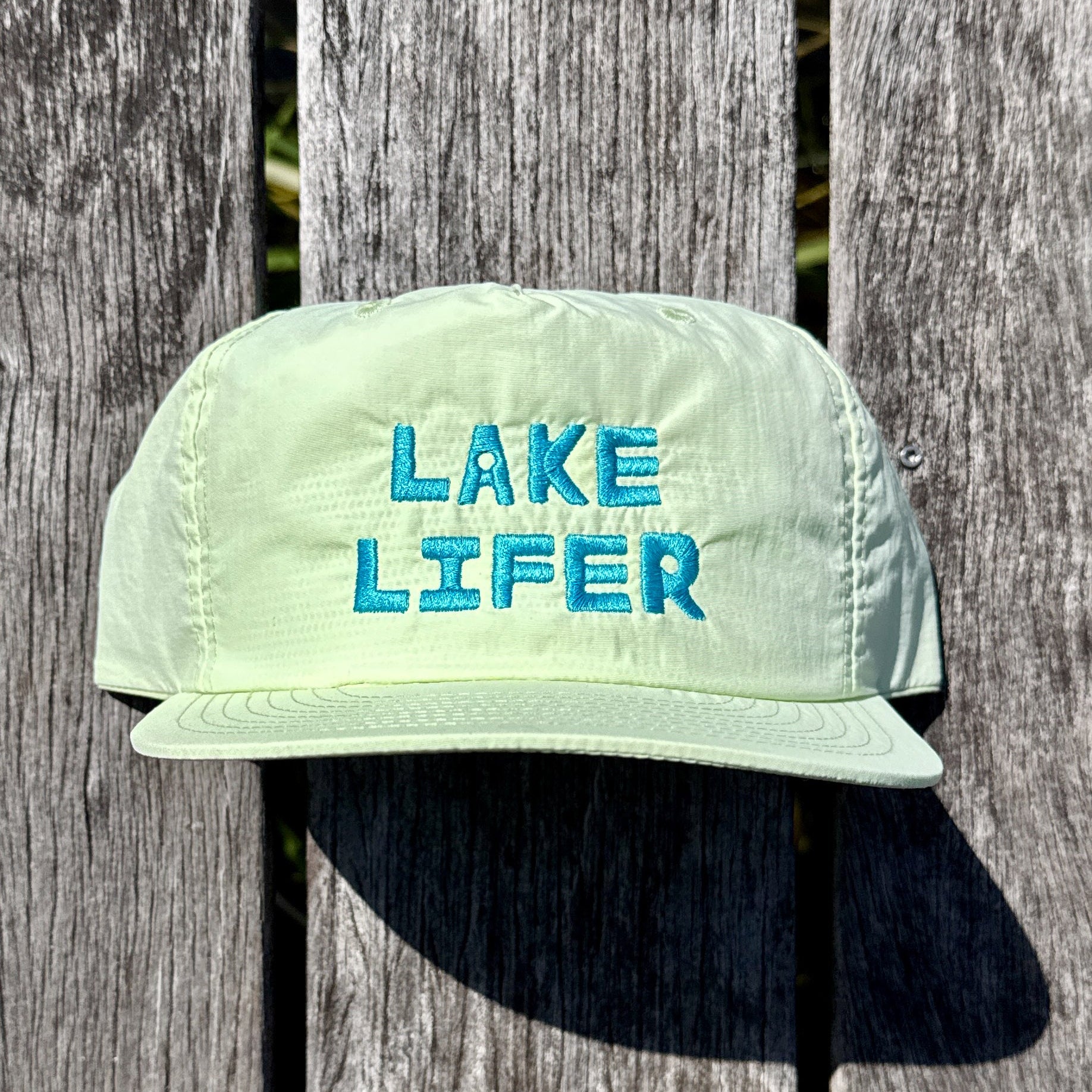 Light green cap with 'Lake Lifer' text on a wooden background