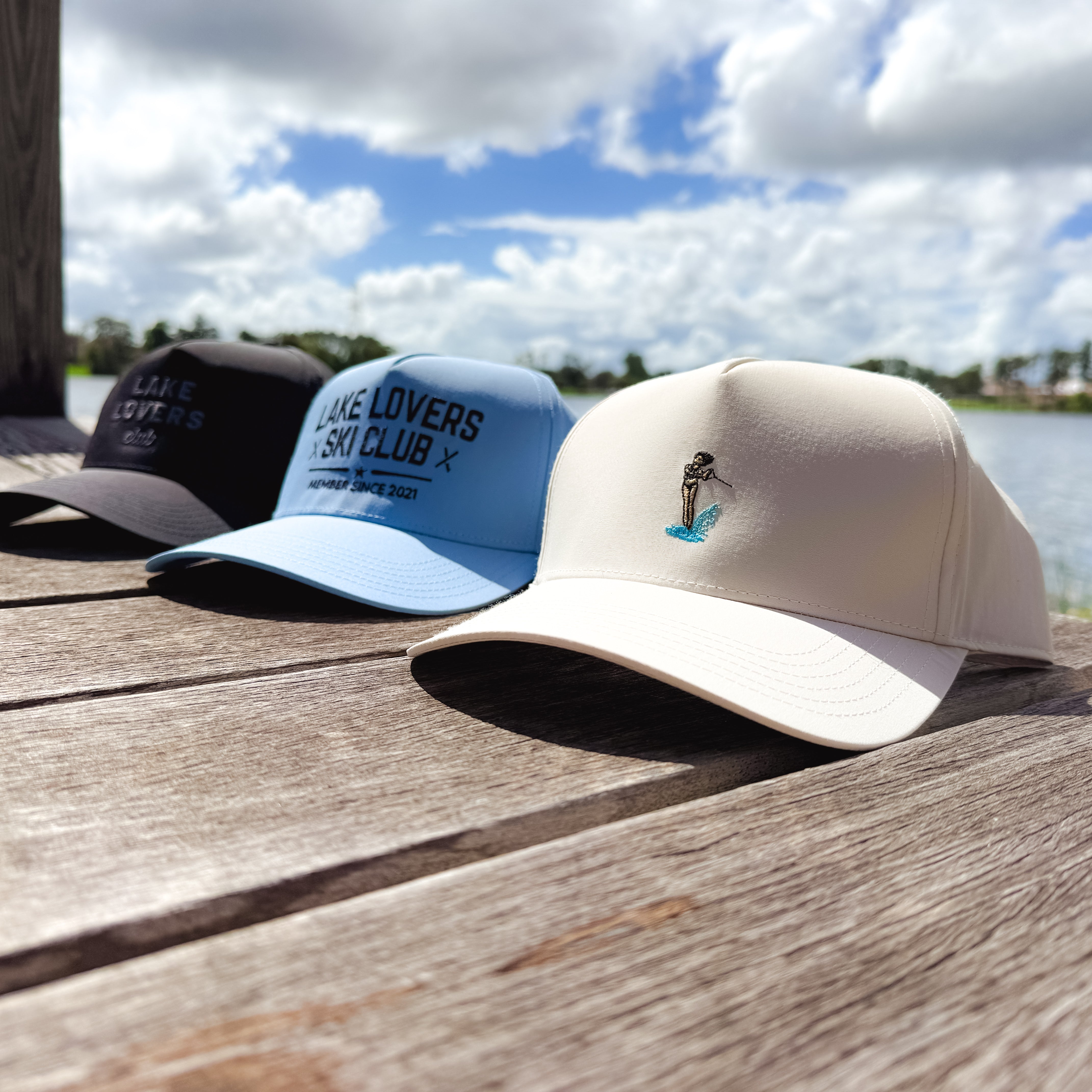 Three baseball caps on a wooden surface with a scenic background