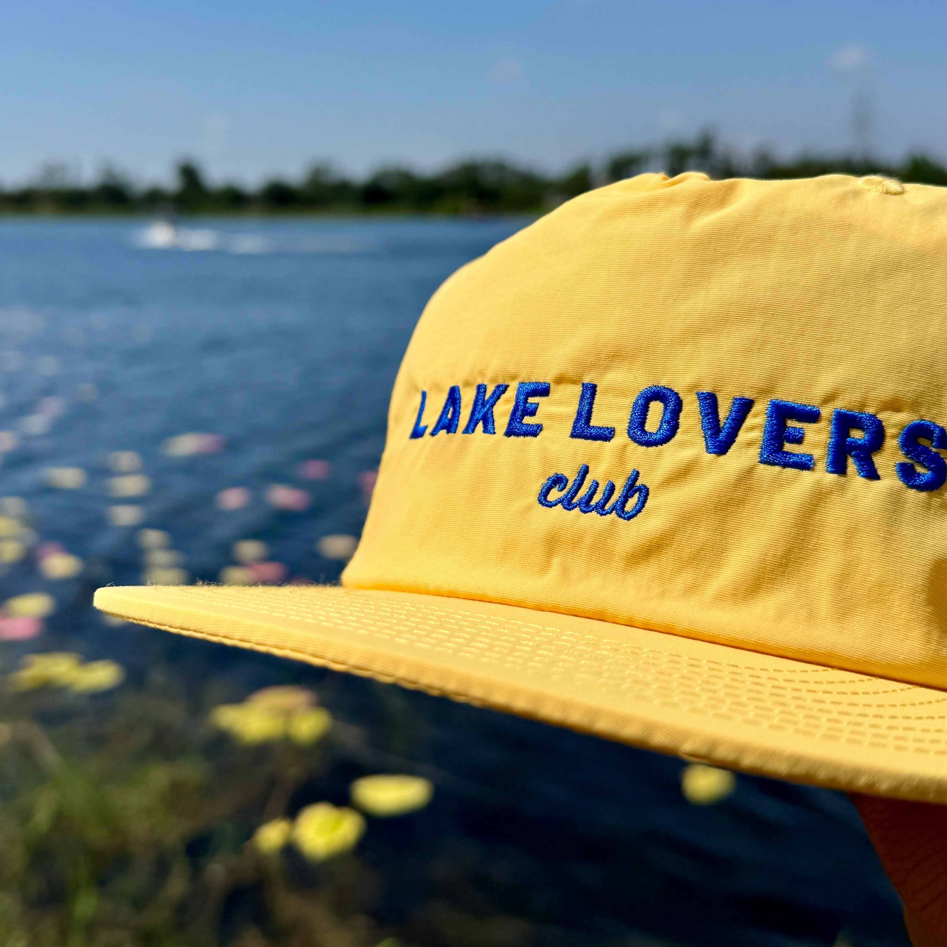 Yellow cap with 'Lake Lovers Club' text against a lake background