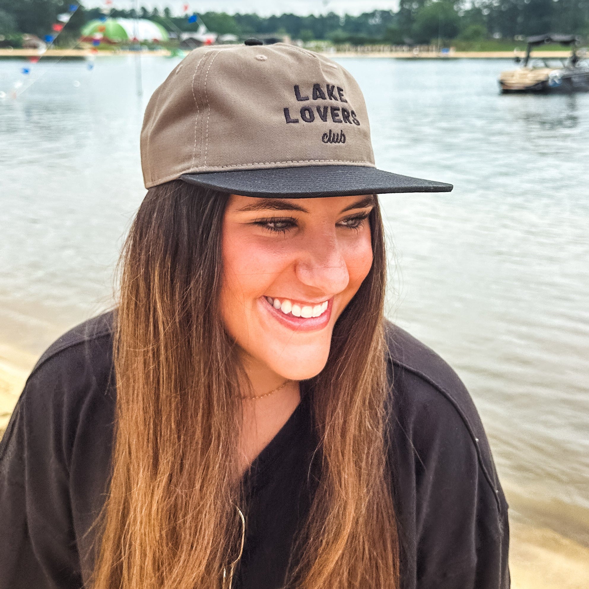 Woman wearing a 'Lake Lovers Club' cap by a lake