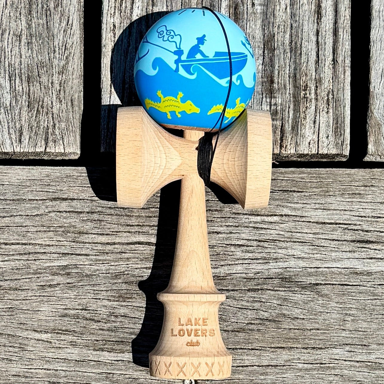 Wooden kendama with a blue and yellow design on a wooden surface