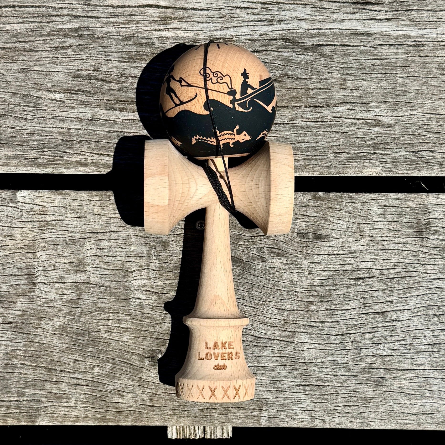 Wooden kendama toy with black and white design on a wooden surface