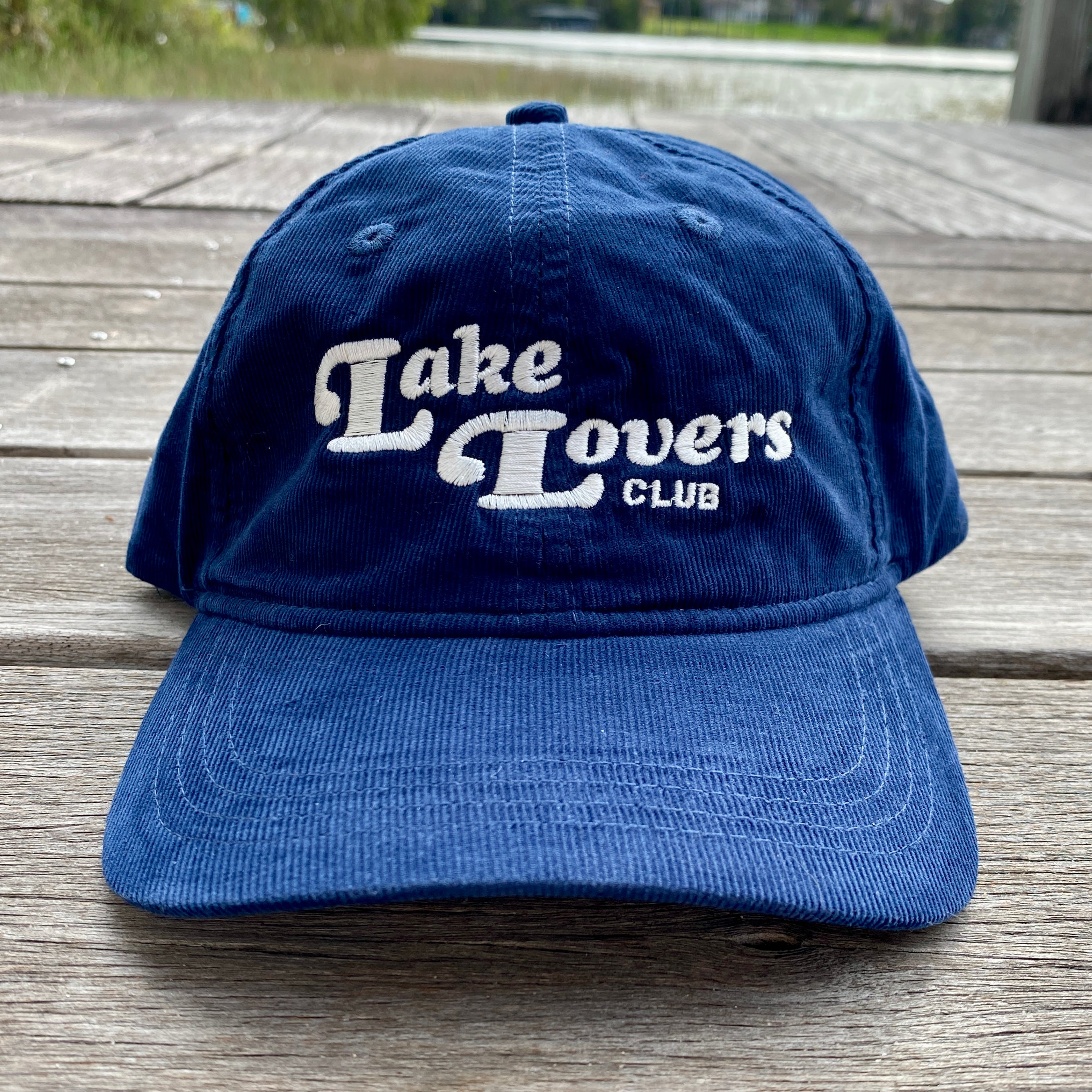 Blue cap with 'Lake Lovers Club' text on a wooden surface