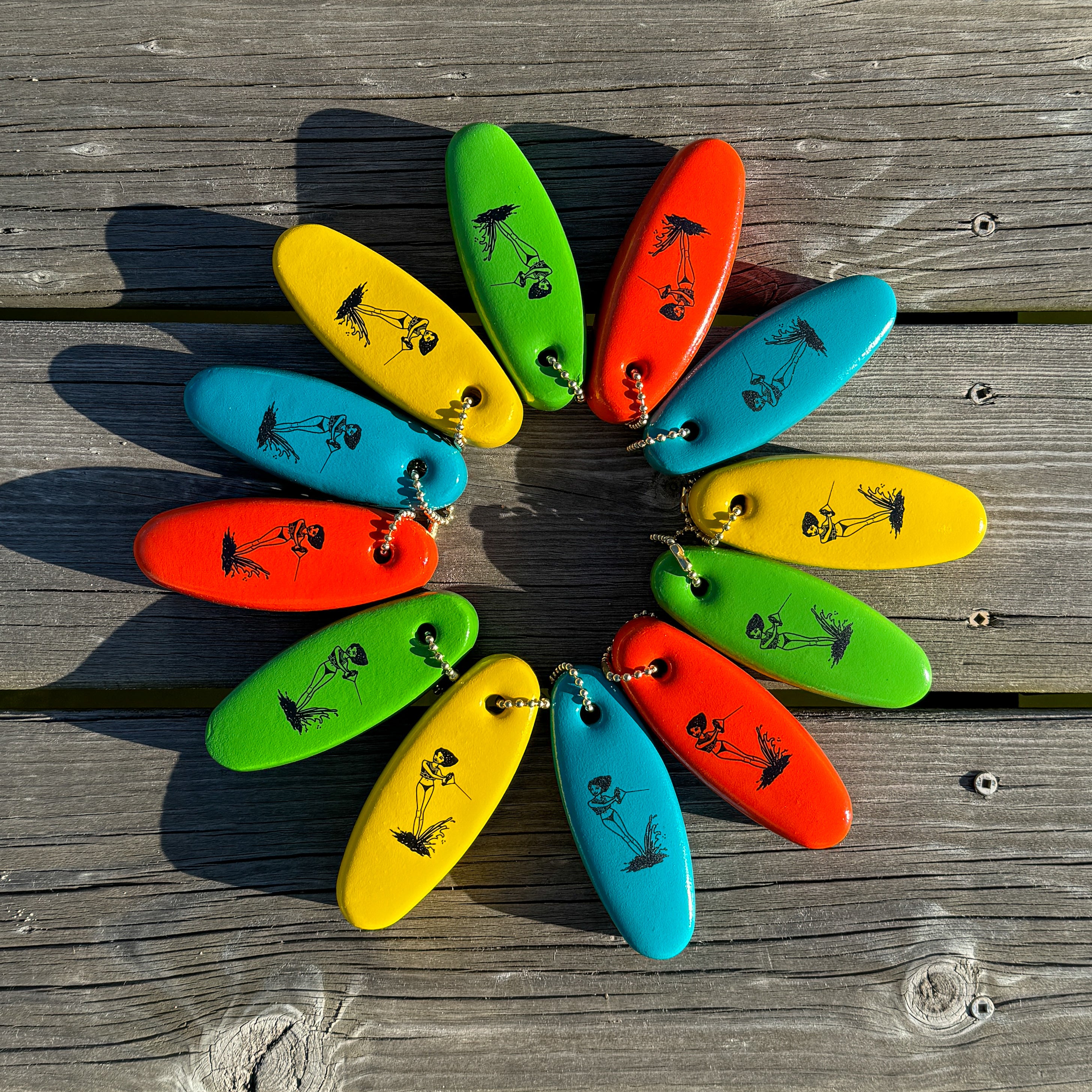 Colorful floater keychains arranged in a circular pattern on a wooden dock.