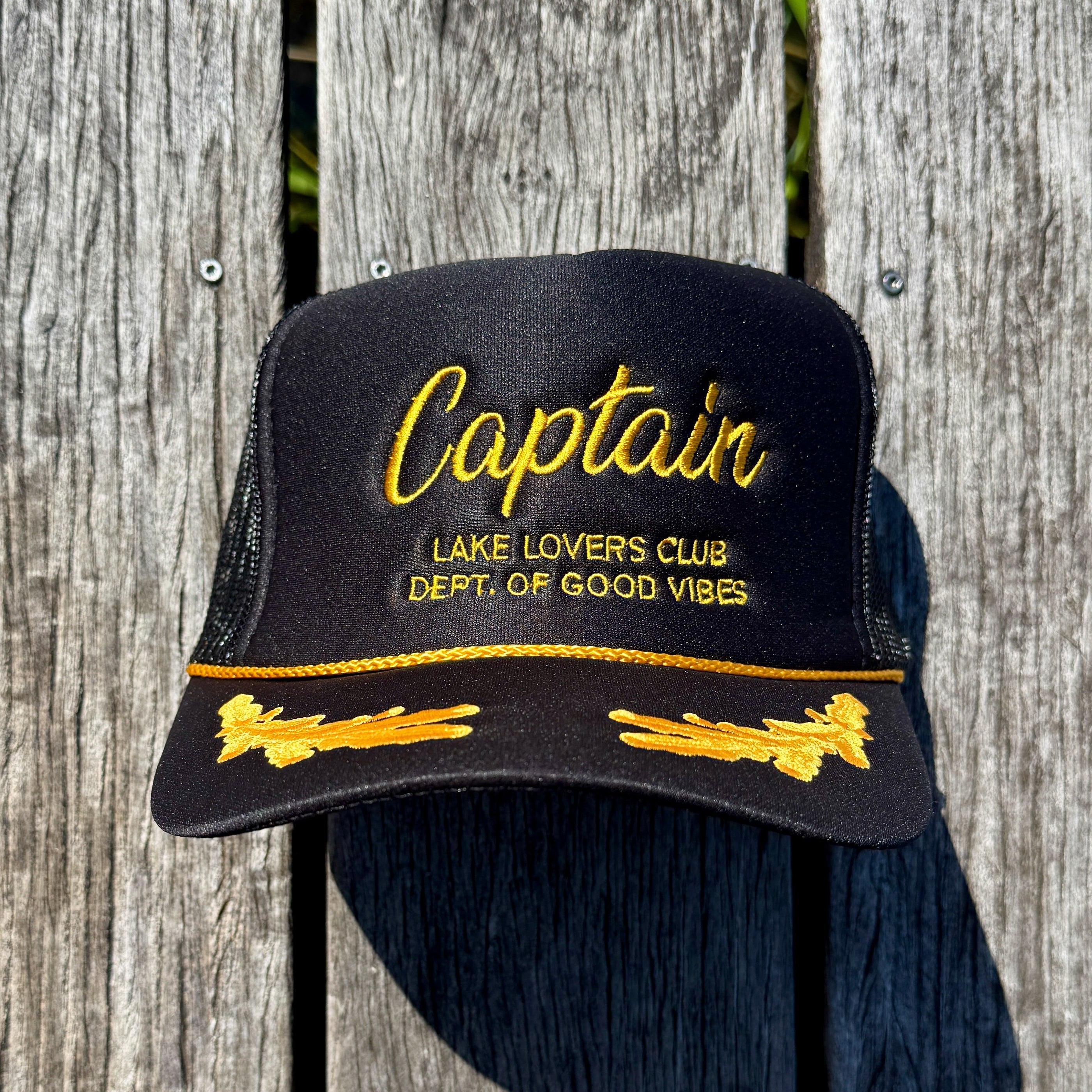 Black cap with yellow text and designs on a wooden background