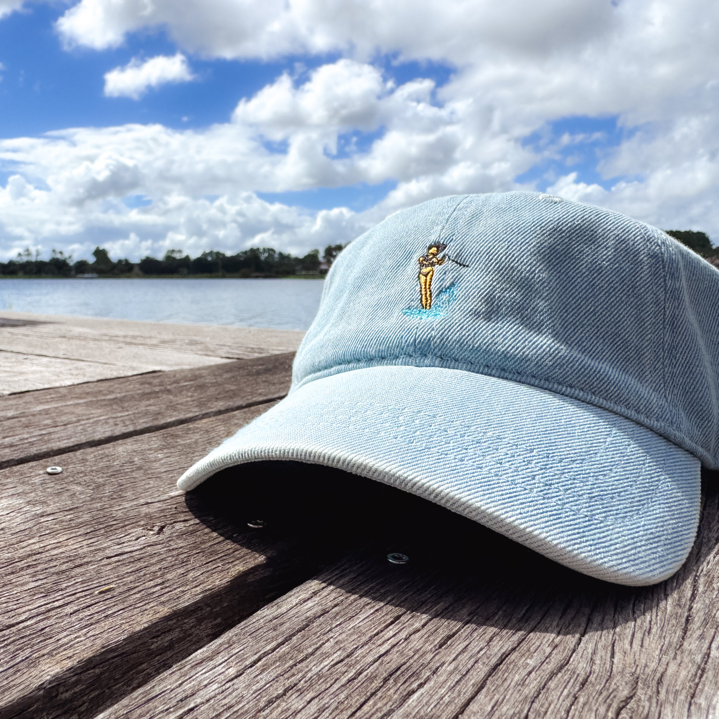 Pink hat on a dock with a waterski girl design embroidered on the front of it.