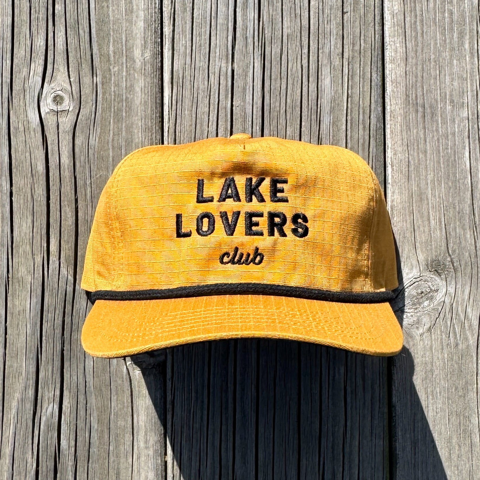 Yellow cap with 'Lake Lovers Club' text on a wooden background