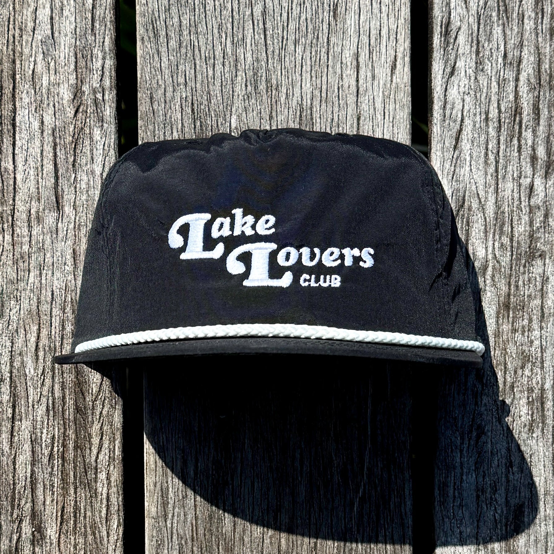 Black cap with 'Lake Lovers Club' text on a wooden background