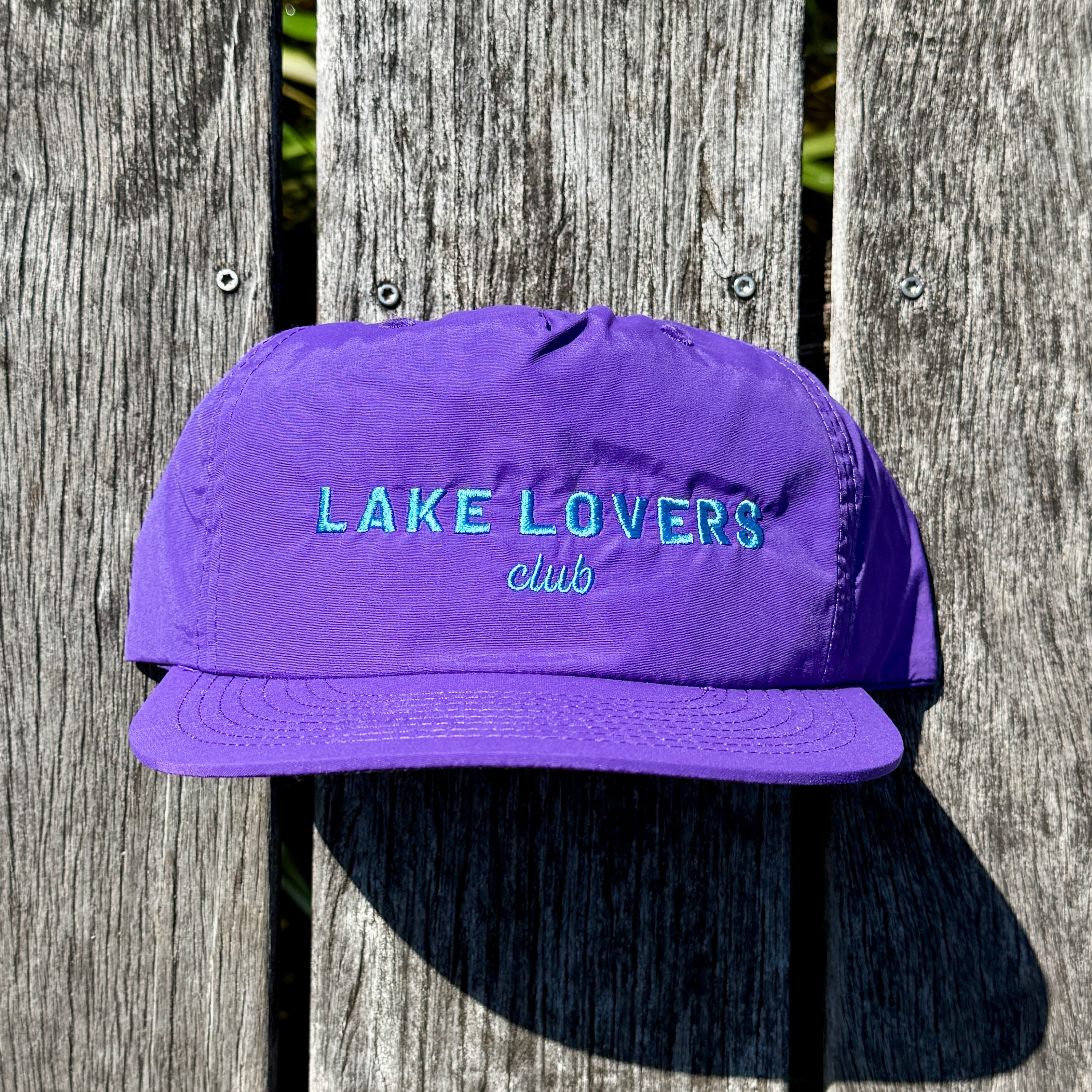 Purple cap with 'Lake Lovers Club' text on a wooden background