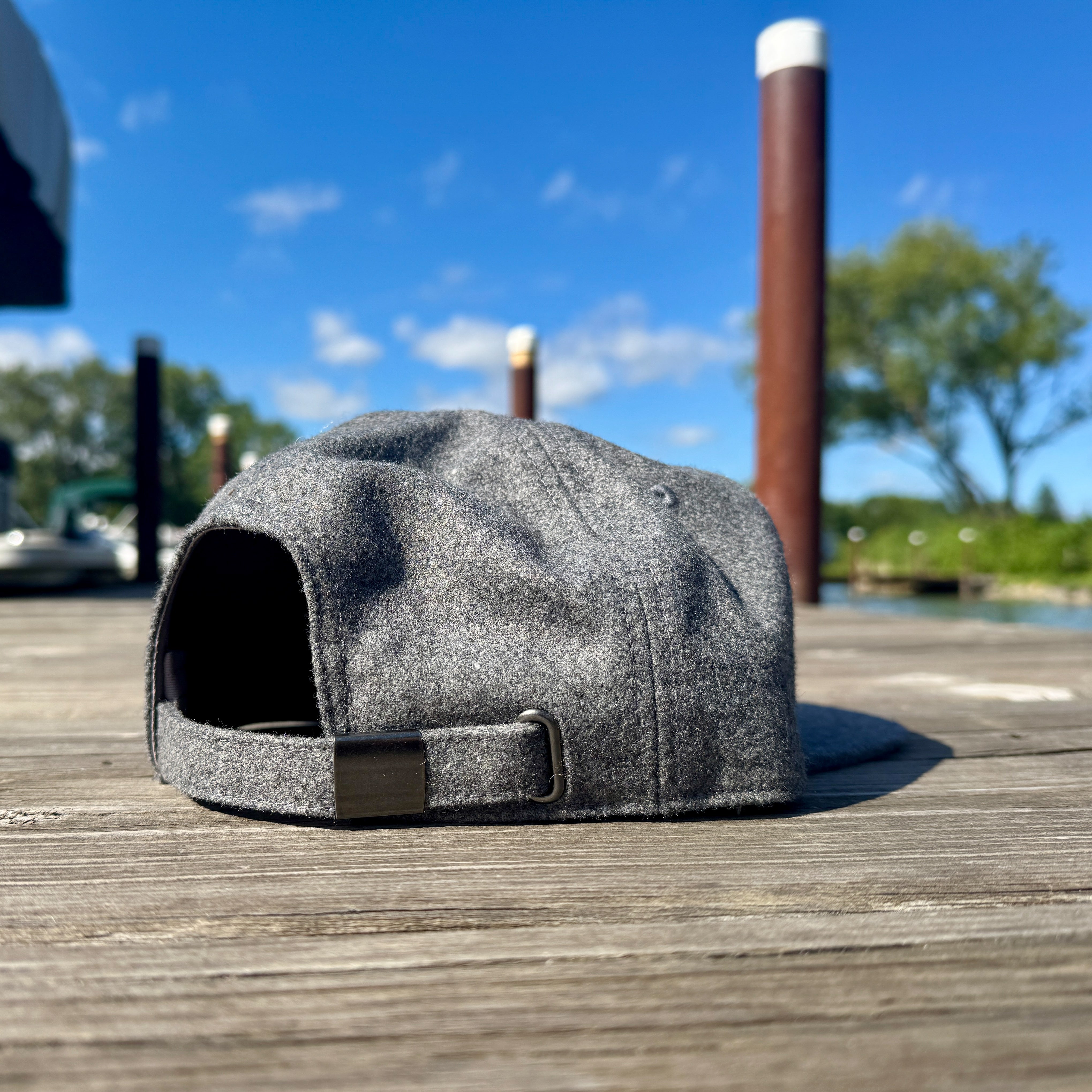 Gray hat on a wooden dock with a blue sky and trees in the background