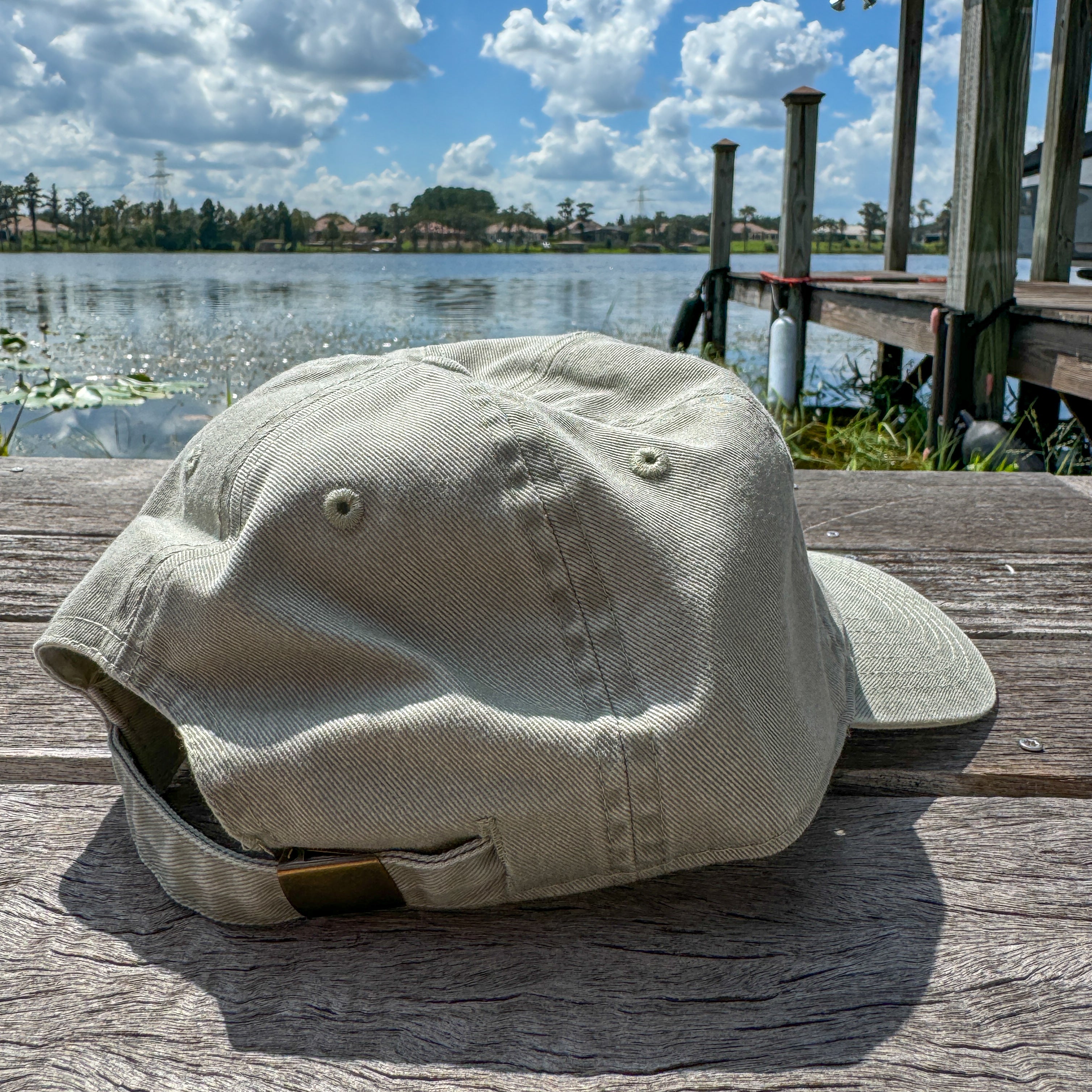 Beige cap on a wooden surface with a lake and dock in the background