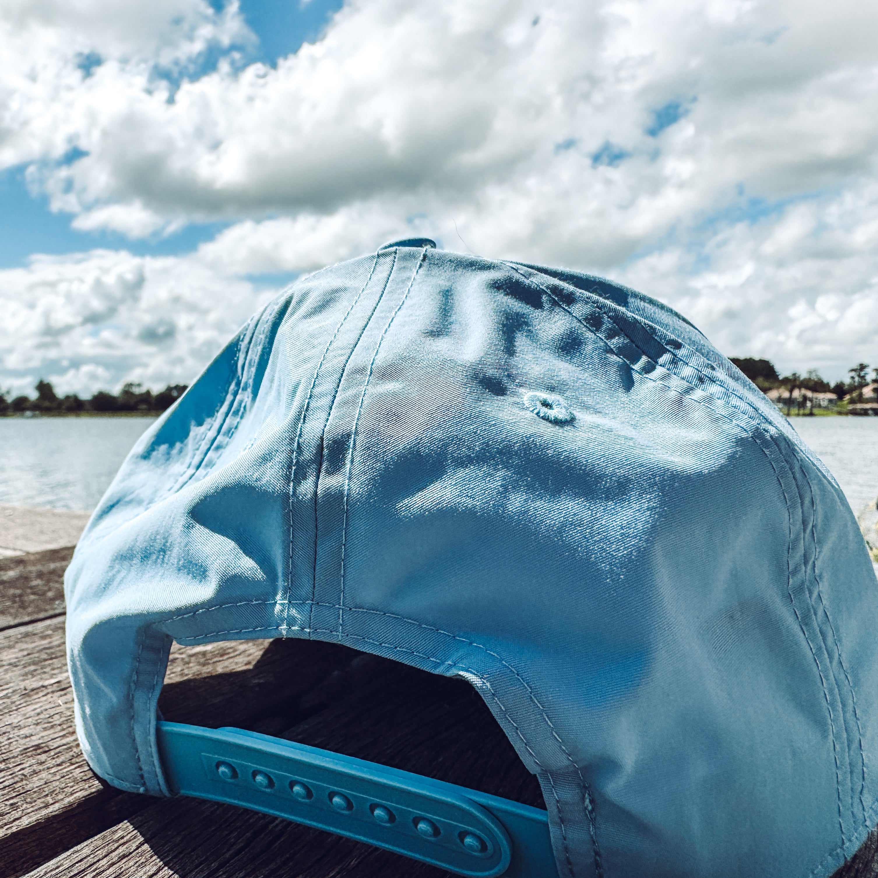 Blue cap on a wooden surface with a cloudy sky and water in the background