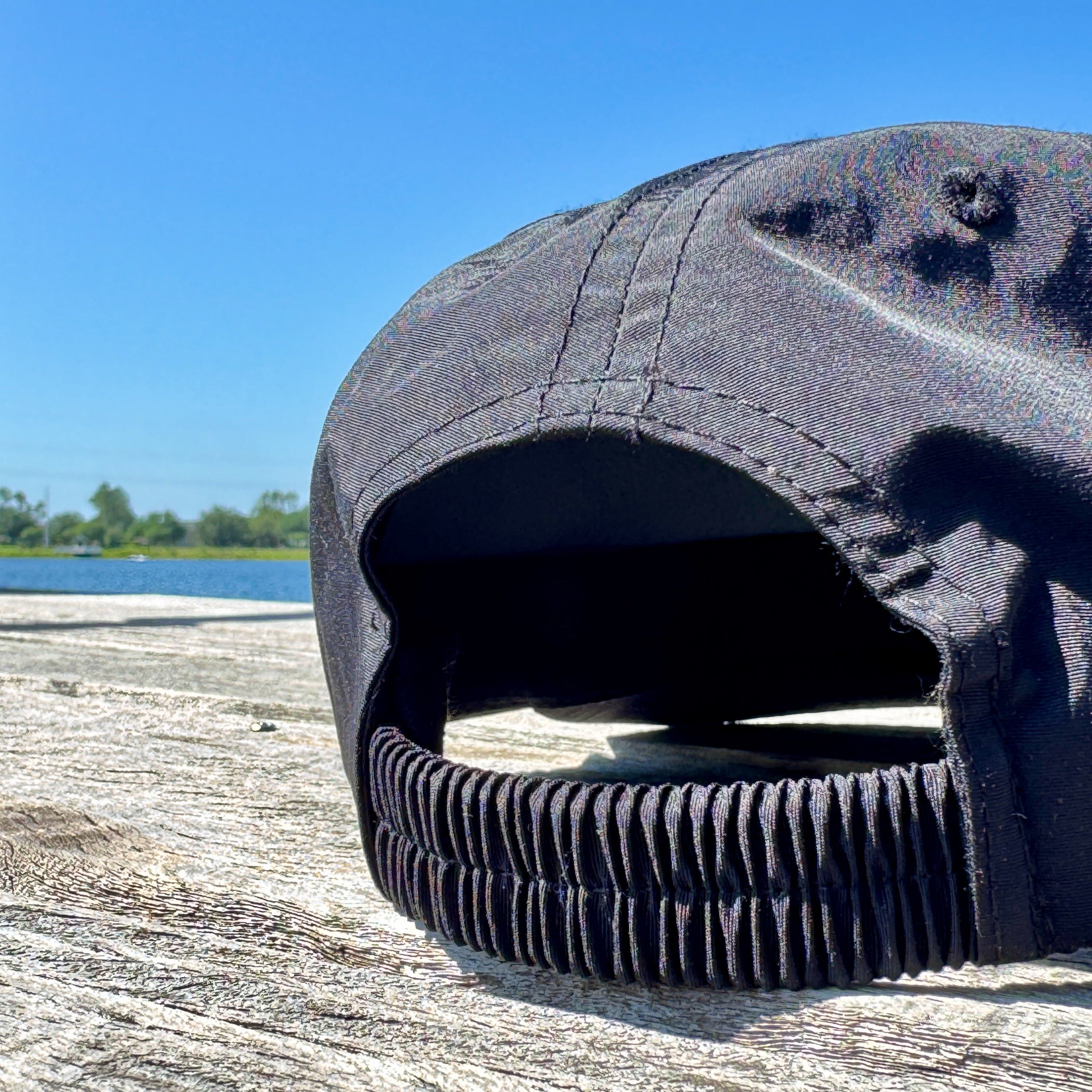 Black rubber duck on a wooden surface with a clear blue sky in the background