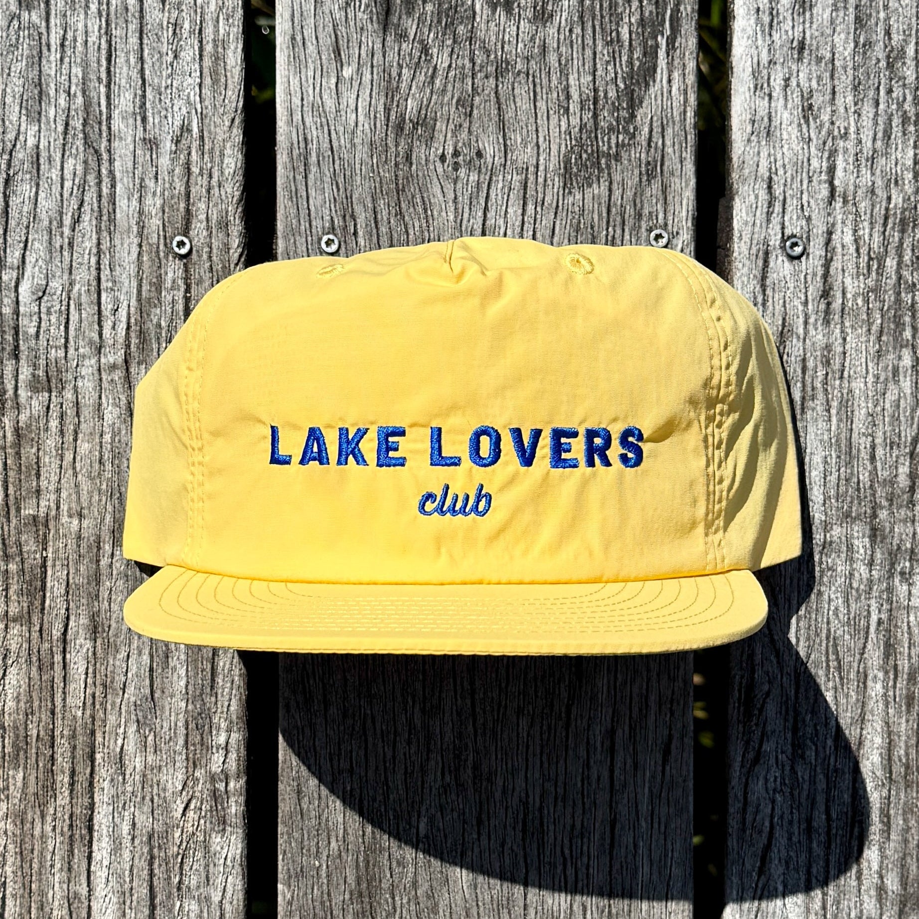 Yellow cap with 'Lake Lovers club' text on a wooden background